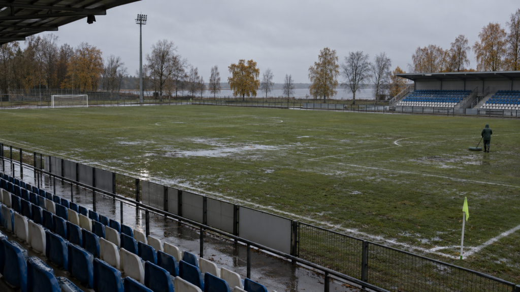 Illustration éditoriale générique d’un petit stade de football sous la pluie, pour un article sur Maardu.