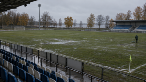Illustration éditoriale générique d’un petit stade de football sous la pluie, pour un article sur Maardu.